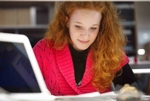 Frau mit rotem Pullover sitzt vor einem Computer