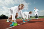Es sind zwei Schüler in Labormänteln zu sehen, die am Start einer Laufbahn aufgestellt sind.