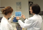 Dr. Kerstin Stemmer bei ihrer Arbeit im Labor mit einer Mitarbeiterin. Beide halten ein Schriftstück in der Hand, das Untersuchungsergebnisse dokumentiert.