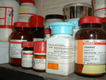 The photo shows several white containers in a laboratory shelf.