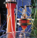 Glass bioreactor filled with a red liquid.