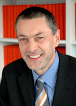 Zu sehen ist das Gesicht und der Oberkörper von Christoph Schächtele, im Hintergrund ein Bücherregal.