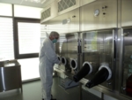 Technische Anlage mit sogenannten Handschuhports, Sicherheits-Ausstülpungen, die sowohl den Schutz des Produkts als auch des Menschen garantieren, der damit Zugang zu einem geschützten Bereich hat und arbeiten kann.