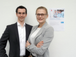 Farbfoto von Dr. Benjamin Streb (rechts) und Elli Mohr (links). Im Hintergrund rechts ist eine Werbeseite für das Fernstudium an die Wand geklebt.