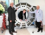 Drei Herren haben sich um das ringförmige Medizintechnik Bauteil aufgestellt
