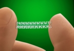 A tiny stent held between thumb and forefinger. The scaffold is many times smaller than a fingernail, is rectangular and consists of several interconnected shafts.