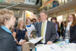 Umweltminister Franz Untersteller steht an einem Messestand und unterhält sich mit Besuchern und Ausstellern.