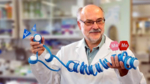 The photo shows a man with glasses holding a blue cord with flags and marks in his hands.