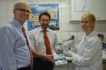 Zu sehen sind drei Mitarbeiter von QIAGEN Lake Constance im Labor mit einem mobilen Diagnosegerät.