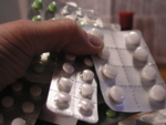 The photo shows a hand holding several packages of tablets