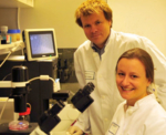 The photo shows two scientists looking into the camera.