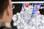 Der Kopf eines Wissenschaftlers vor einem Computerbildschirm mit Molekülmodell.