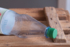The photo shows a plastic bottle on a wooden box.